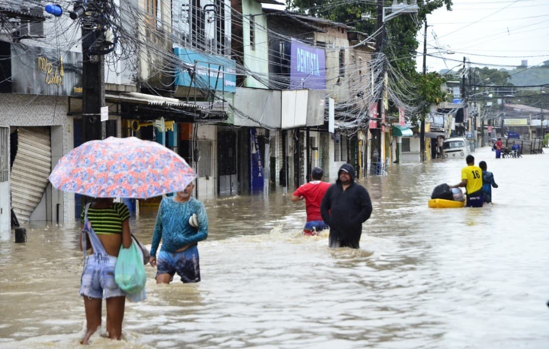 Pessoas tentando passar pela Estrada do Caenga, que estava completamente alagada