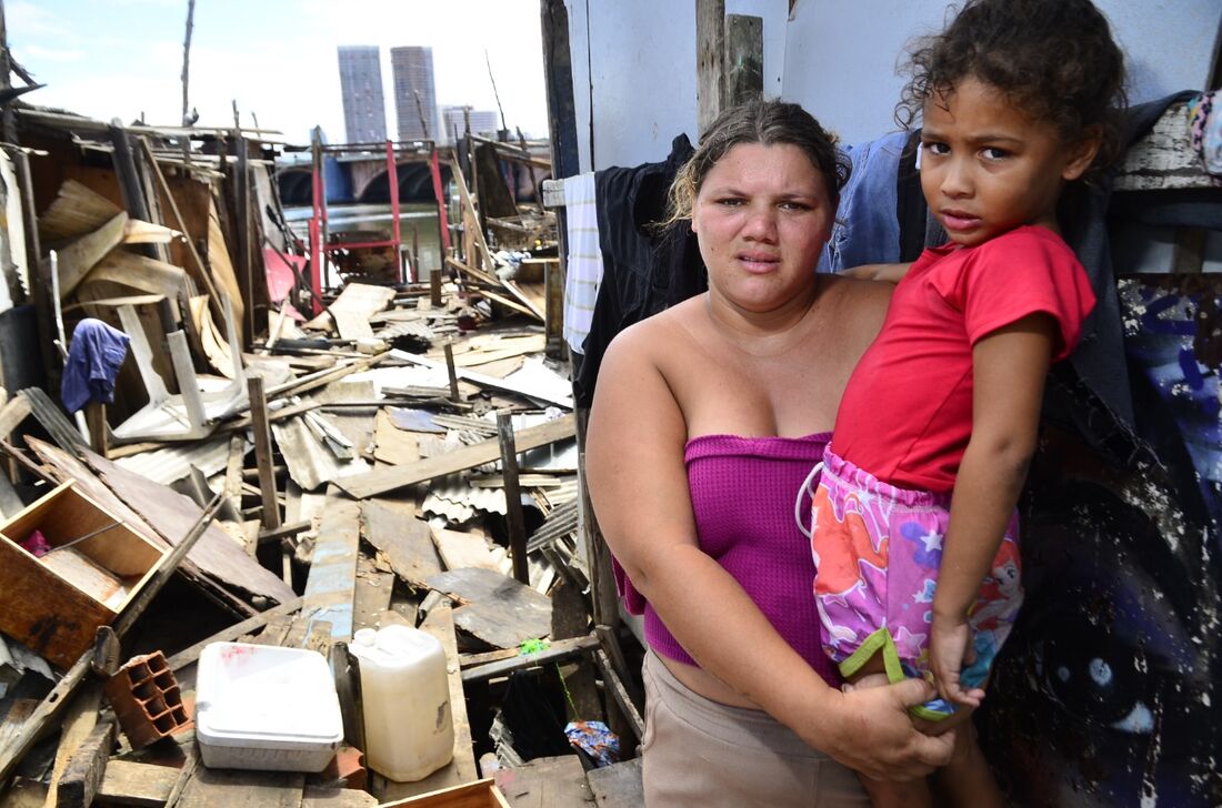 Janecleide Fernandes, 26, com a filha, 5, em frente aos destroços após incêndio no Pina