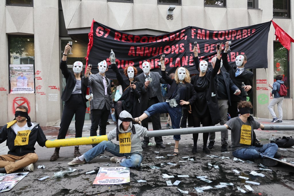 Ativistas climáticos bloquearam nesta segunda-feira (27) durante várias horas as portas da entrada à sede do Fundo Monetário Internacional (FMI) em Paris para "reivindicar a anulação da dívida dos países do sul".  "G7 responsável, FMI culpado, anulem a dí