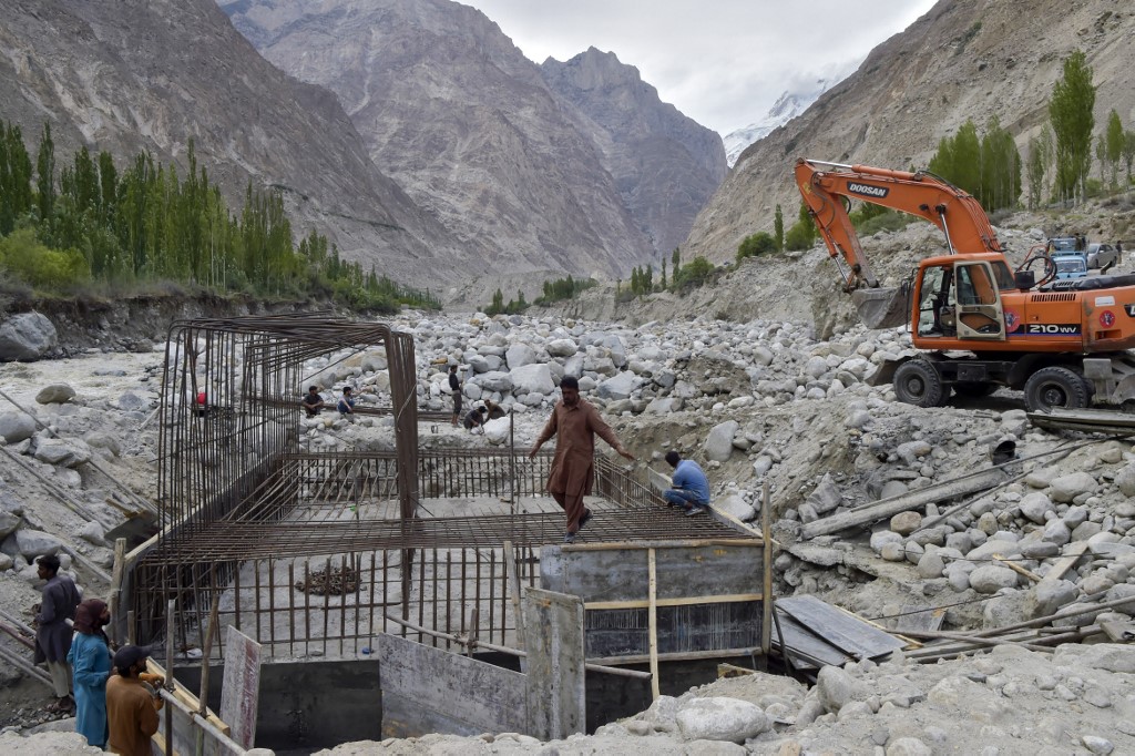 Nesta foto tirada em 9 de junho de 2022, trabalhadores da construção civil constroem uma ponte temporária após uma explosão de lago por causa de um derretimento de uma geleira que varreu a ponte principal na vila de Hassanabad, na região de Gilgit-Baltist