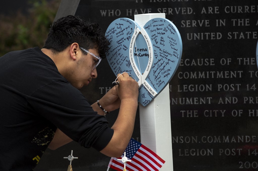 Um enlutado escreve em um memorial para as vítimas de um tiroteio em massa em um desfile de 4 de julho, em 6 de julho de 2022 em Highland Park, Illinois