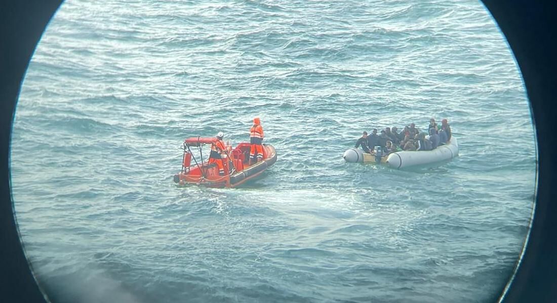 Bote resgatando migrantes no Canal da Mancha, visto por um binóculo