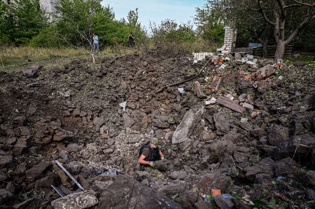 Um sapador ucraniano examina uma cratera após um ataque de mísseis na vila de Rohan, perto de Kharkiv, em 21 de agosto de 2022, em meio à invasão russa da Ucrânia