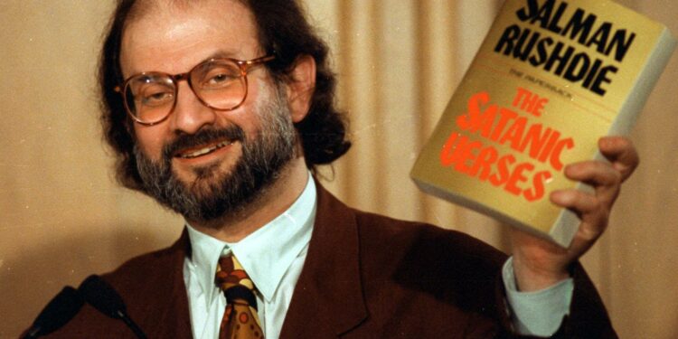 O escritor britânico Salman Rushdie com seu livro 'Os versos satânicos'