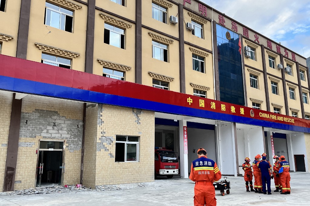 Bombeiros se reúnem perto de uma parede danificada de um corpo de bombeiros após um terremoto de magnitude 6,6 em Hailuogou, na província de Sichuan, sudoeste da China, em 5 de setembro de 2022