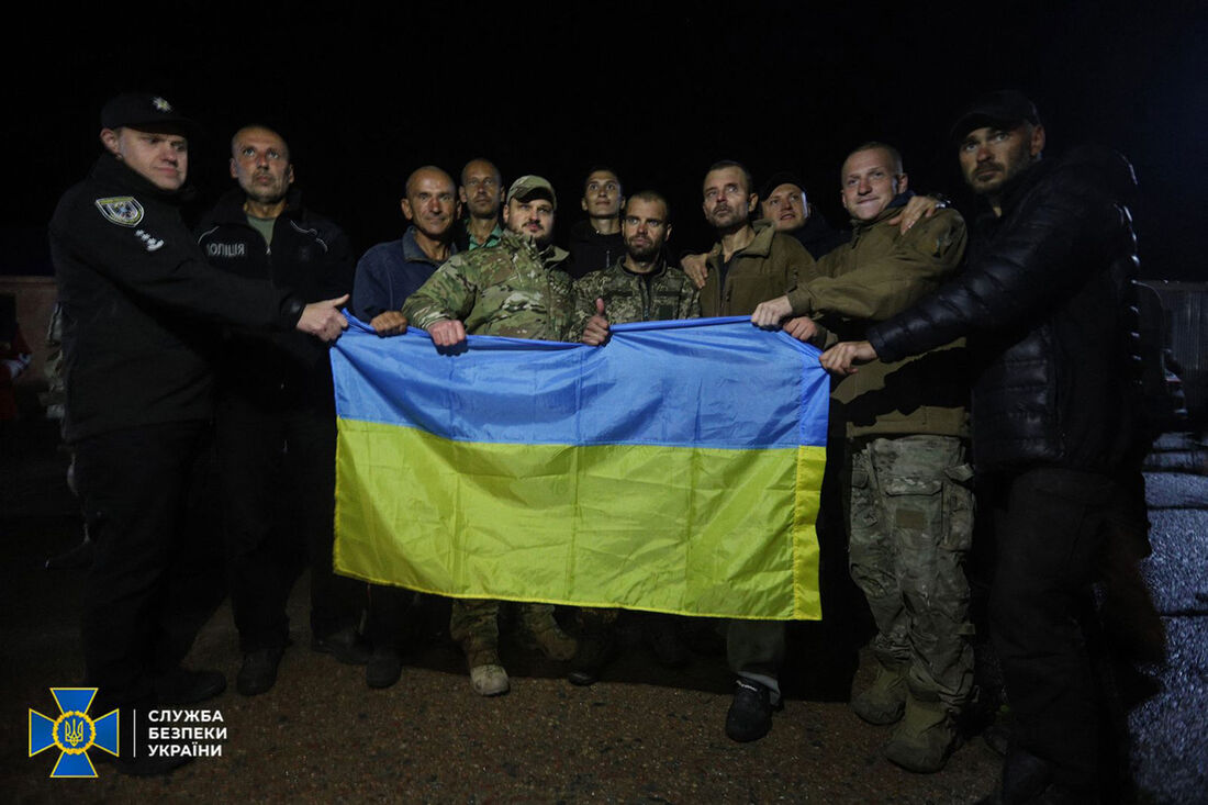 Prisioneiros ucranianos com bandeira ucraniana após troca na região de Chernigiv