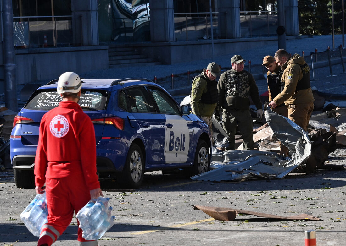 Membros da polícia ucraniana examinam um carro destruído no centro de Kiev após vários ataques russos