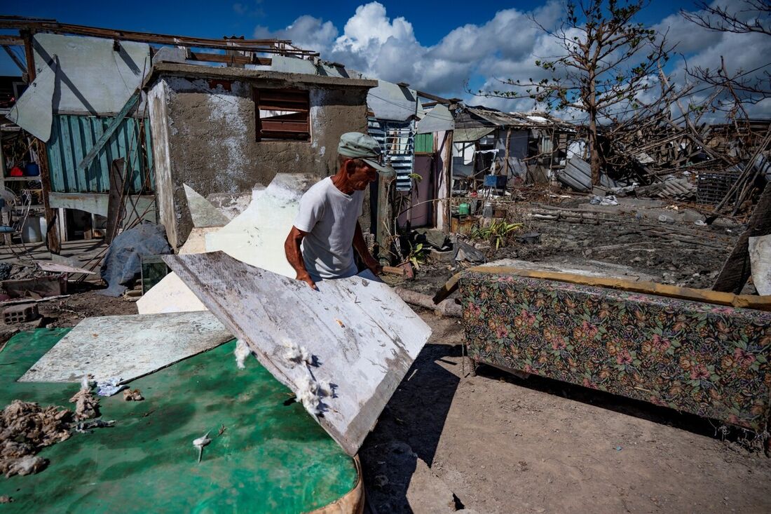 Homem recolhendo destroços do furacão Ian, em Cuba