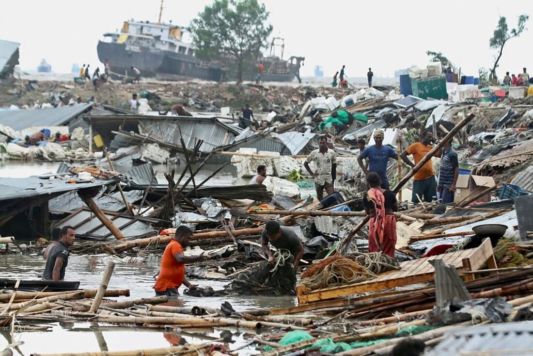 Habitantes buscam por bens e parentes após a passagem do ciclone Sitrang na cidade de Chittagong, Bangladesh