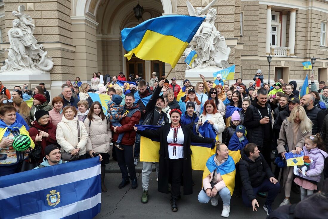 Moradores de Kherson que vivem temporariamente em Odessa, segurando bandeiras ucranianas, comemoram a libertação de sua cidade natal