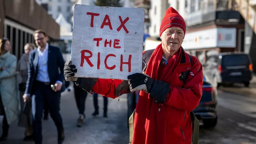 O milionário britânico Phil White segura um cartaz onde se lê: "Taxe os ricos" durante o Fórum Econômico Mundial