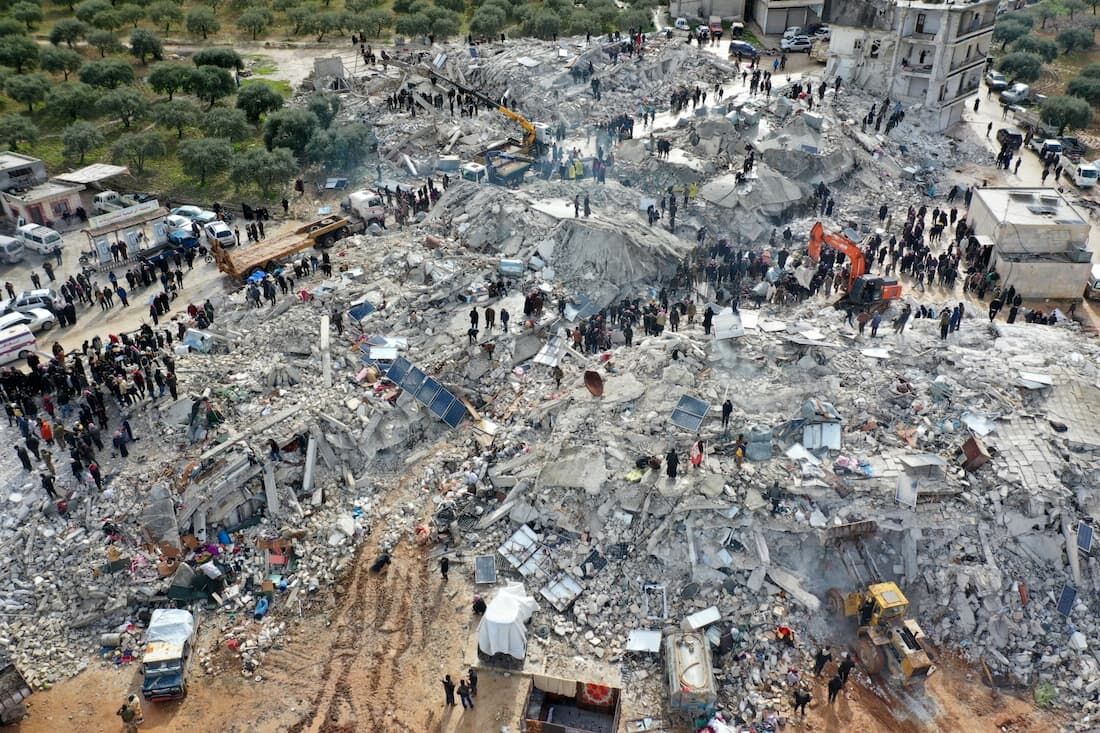 Esta vista aérea mostra residentes em busca de vítimas e sobreviventes em meio aos escombros de prédios desabados após um terremoto na vila de Besnia, perto de Harim, na província de Idlib, no noroeste da Síria