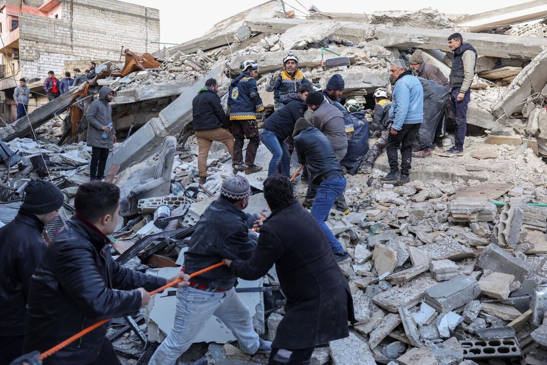 Equipes de resgate vasculham os escombros de edifícios em busca de vítimas e sobreviventes na vila de Azmarin, na província de Idlib, no noroeste da Síria, controlada pelos rebeldes, na fronteira com a Turquia, após um terremoto, em 7 de fevereiro de 2023