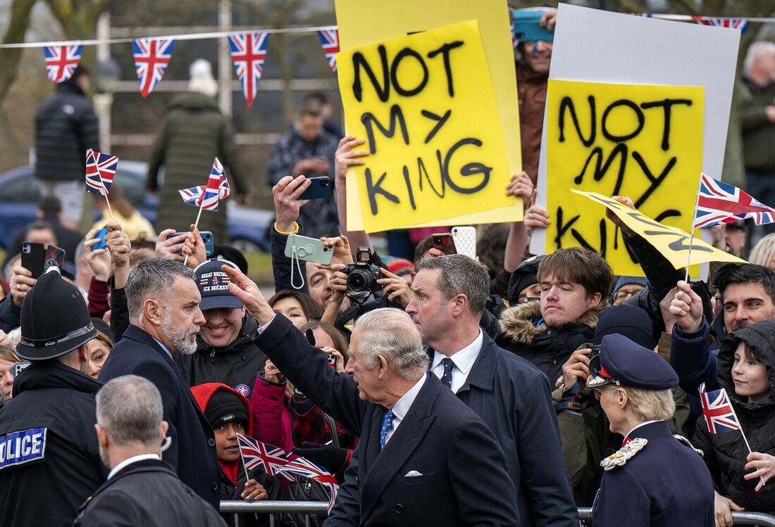 Manifestantes seguram cartazes dizendo "Não é meu rei" enquanto o rei da Grã-Bretanha Carlos III (C) encontra simpatizantes ao chegar à Igreja de Cristo, a pedra angular em Milton Keynes, ao norte de Londres, em 16 de fevereiro de 2023, para participar de