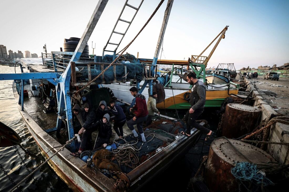 O pescador palestino Jihad al-Hissi e os filhos trabalham no barco em um porto da cidade de Gaza.