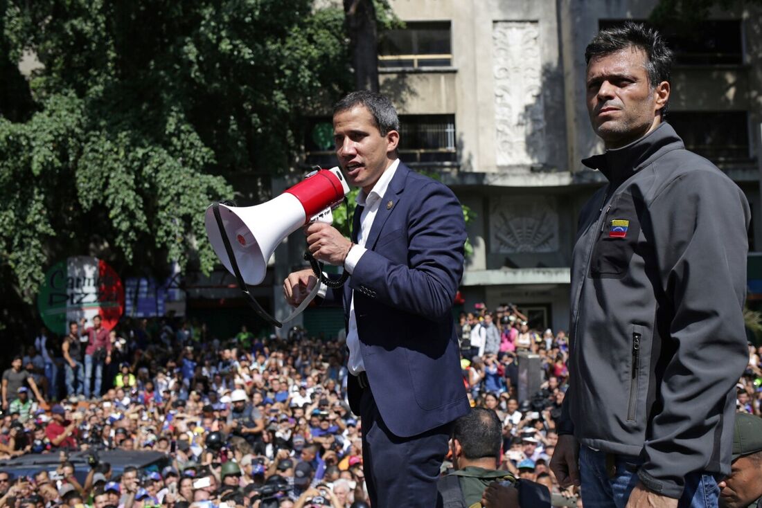 Nesta foto de arquivo tirada em 30 de abril de 2019, o líder da oposição venezuelana e autoproclamado presidente interino Juan Guaido (C) fala com apoiadores ao lado do político de oposição Leopoldo Lopez, que foi colocado em prisão domiciliar