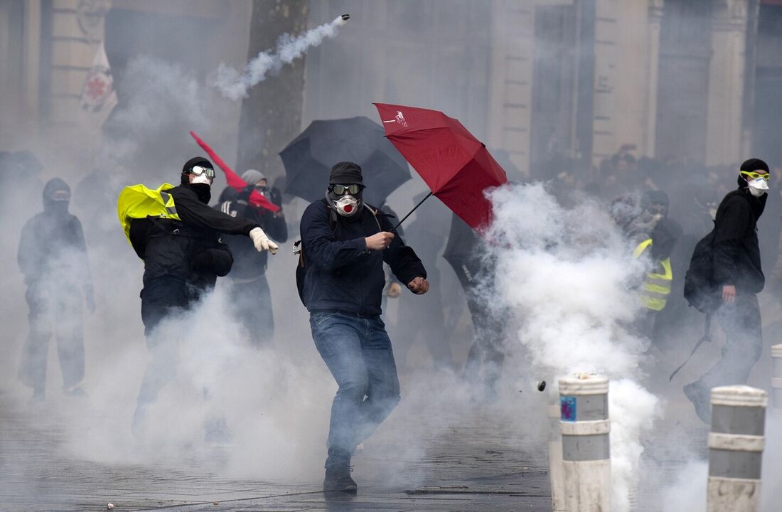 Um manifestante se protege com um guarda-chuva do gás lacrimogêneo durante uma manifestação em Rennes, noroeste da França, em 7 de março de 2023, no sexto dia de manifestações nacionais organizadas desde o início do ano contra a reforma da previdência do 