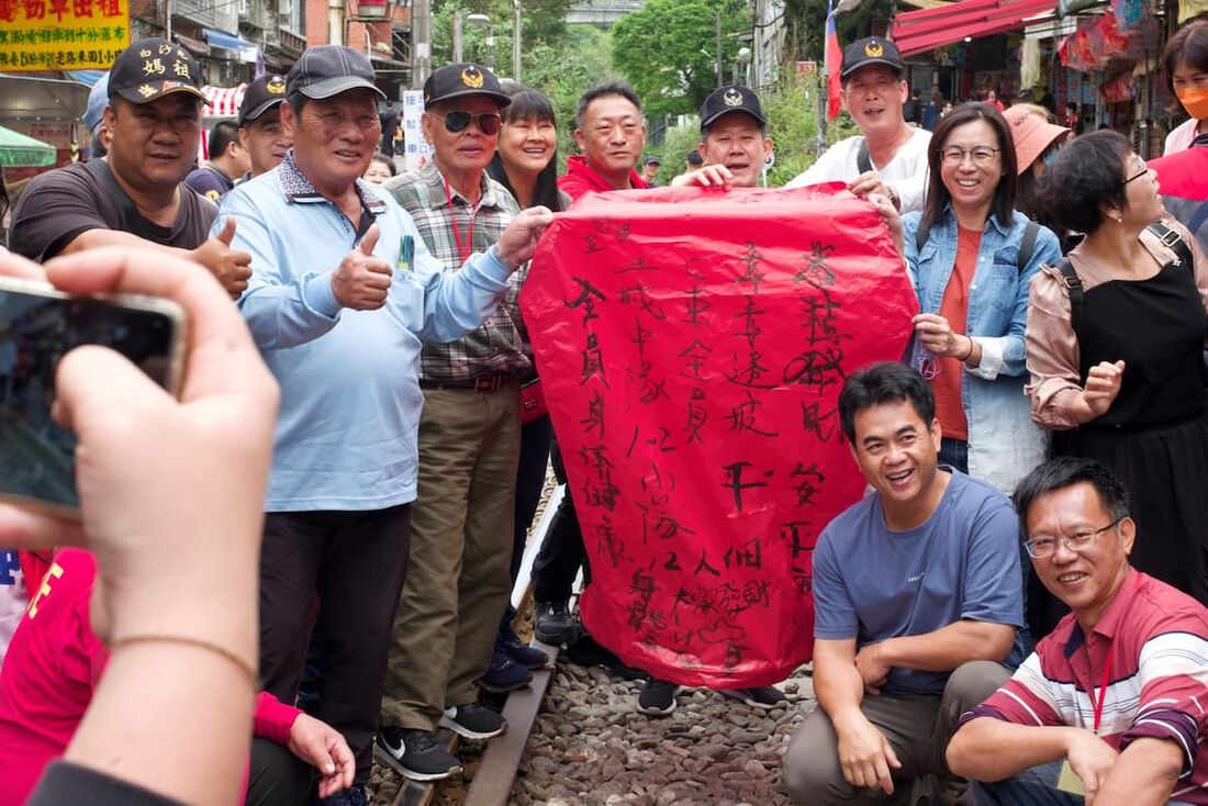 Pessoas posam para fotos com uma lanterna do céu com uma mensagem de paz em Taipei, capital de Taiwan