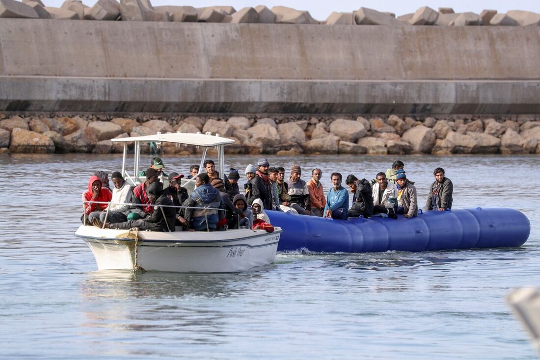 Barcos que transportam migrantes de diferentes nacionalidades entram em um porto na área de Garabulli após serem resgatados no mar pela Guarda Costeira da Líbia.