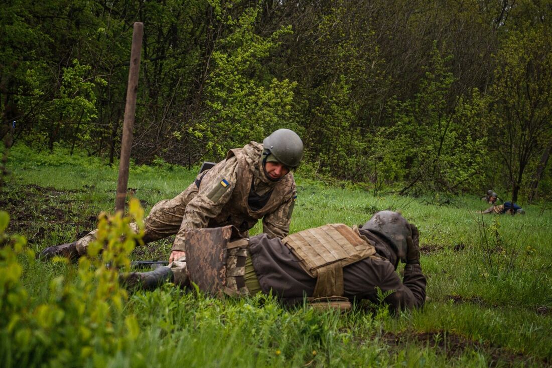 Soldados ucranianos caem no chão para se proteger durante bombardeio perto da cidade de Bakhmut, na região de Donetsk, na linha de frente,