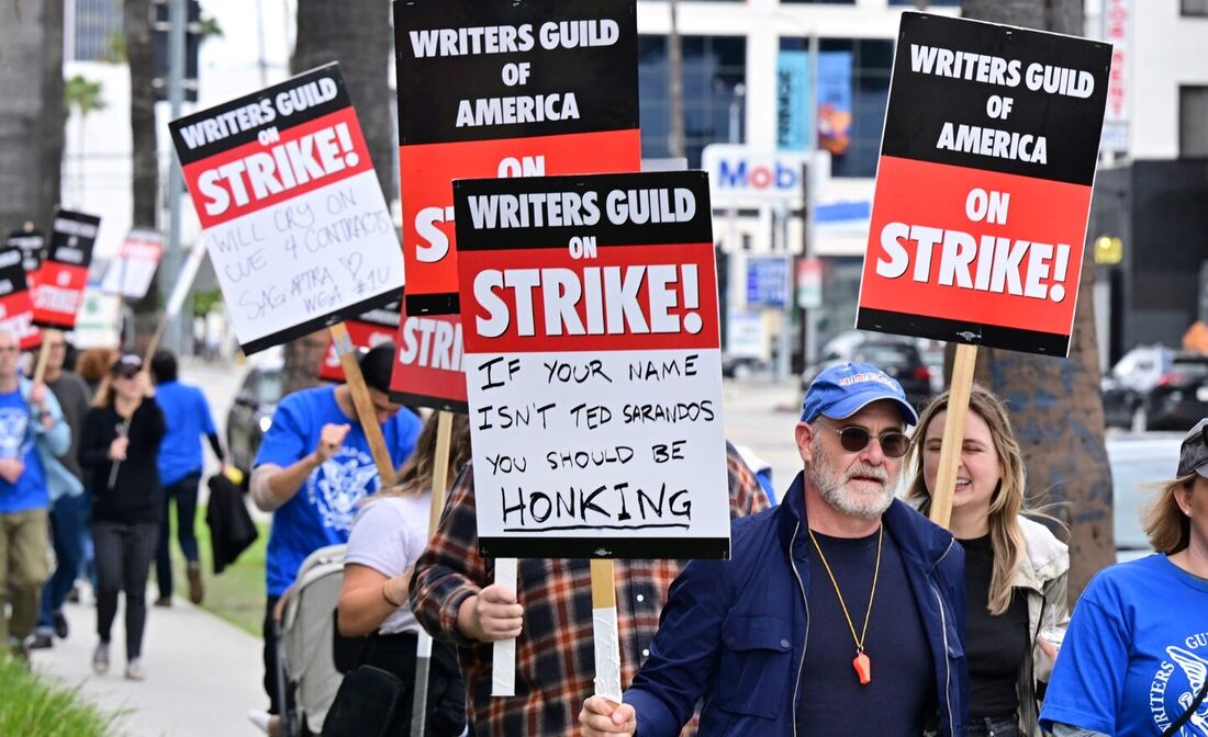 Escritores seguram cartazes no piquete no quarto dia da greve do Writers Guild of America enquanto marcham pela Netflix em Hollywood, Califórnia, em 5 de maio de 2023