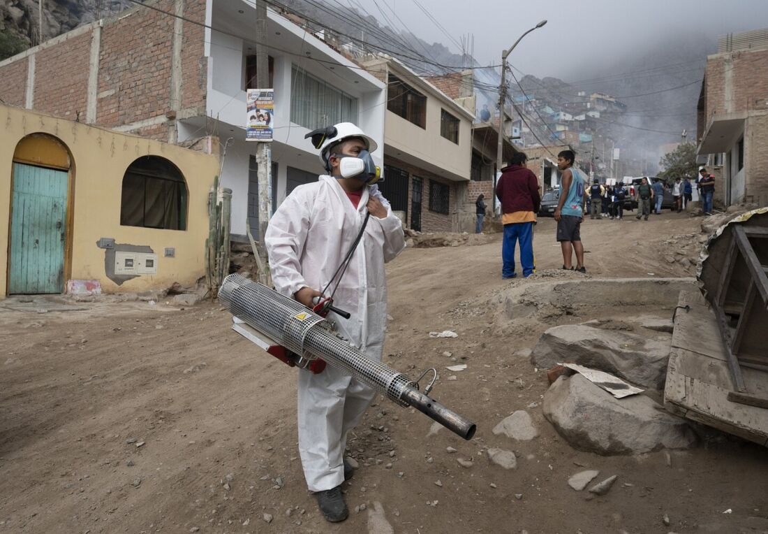 Um membro de uma brigada de saúde fumiga uma casa contra o vírus da dengue em uma favela nas colinas do distrito de San Juan de Lurigancho, Lima, em 11 de maio de 2023