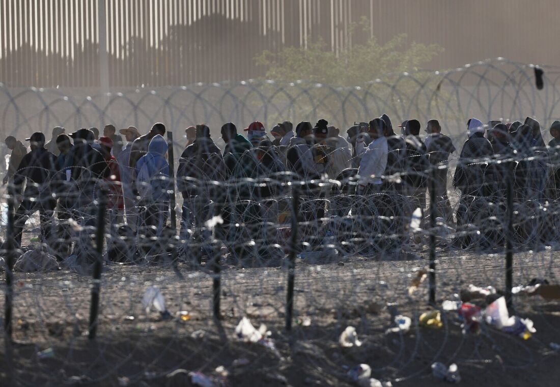 Migrantes aguardam nas margens do Rio Grande para serem processados pela Patrulha de Fronteira do Setor de El Paso, Texas.