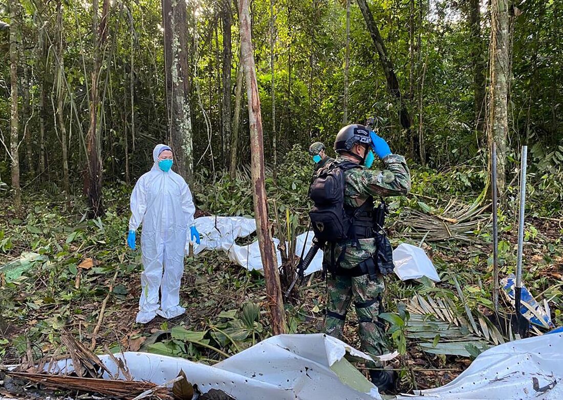 Exército colombiano mostrando um cientista forense (L) e soldados ao lado dos destroços de uma aeronave que caiu na floresta amazônica colombiana no município de Solano, departamento de Caquetá