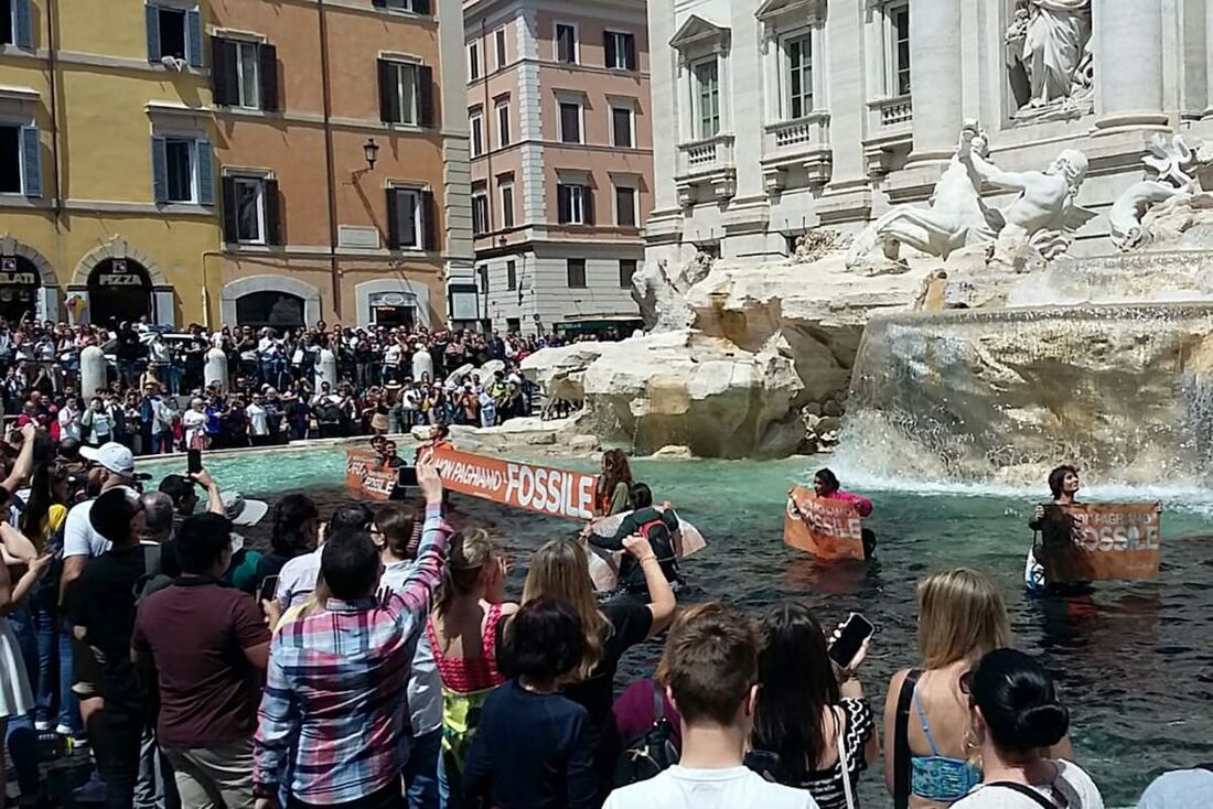 Ativistas seguram faixas na histórica Fontana di Trevi, em Roma e tingem a água de preto