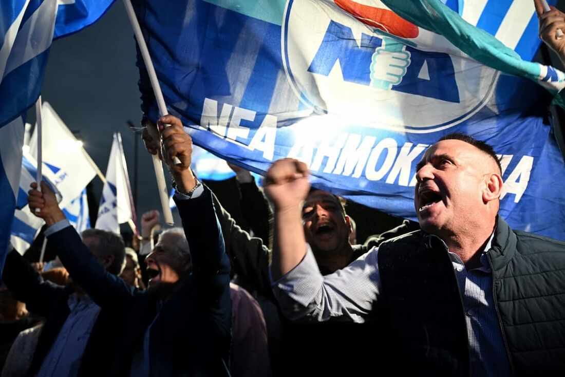 Pessoas agitam a bandeira da Nova Democracia após o anúncio do resultado das primeiras urnas na Grécia