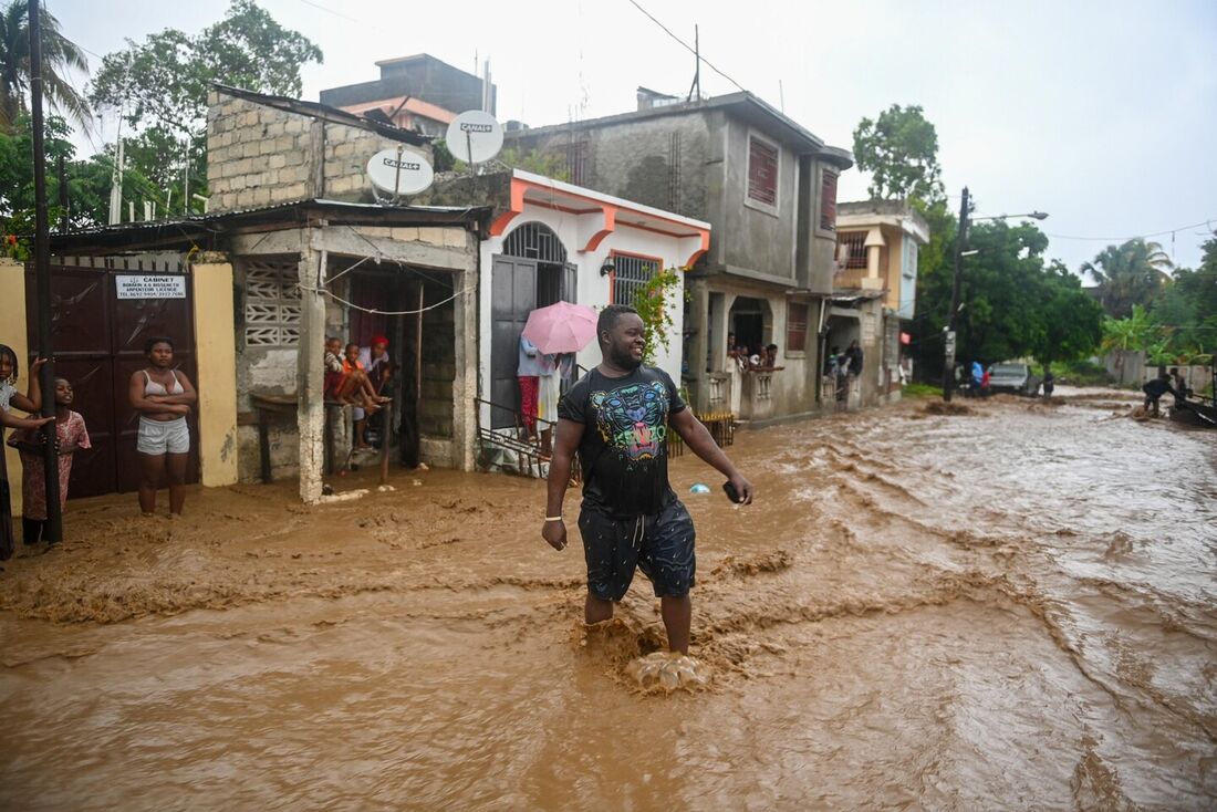 Residente atravessa estradas inundadas nos bairros de Petit-Goâve, Haiti, em 3 de junho de 2023, durante fortes chuvas no Haiti