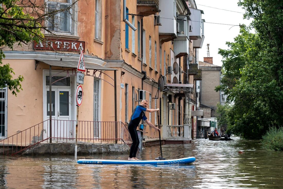 Residente local navega em um sup board durante uma evacuação de uma área inundada em Kherson