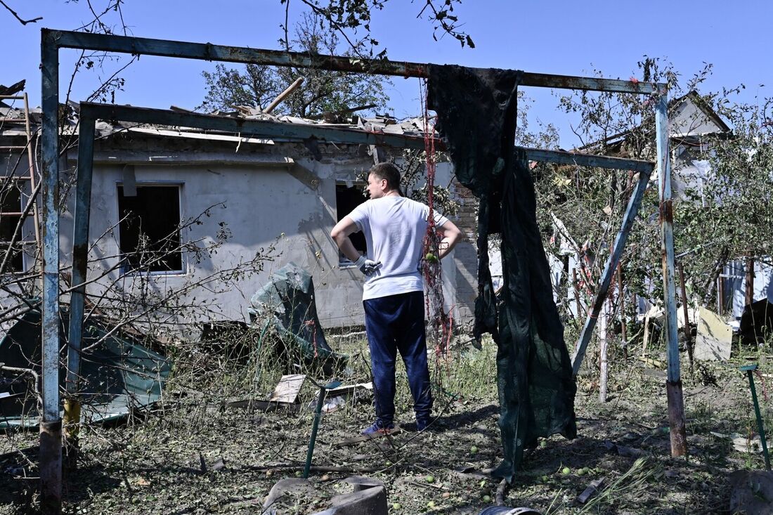 Um morador no quintal de uma casa destruída após um ataque de míssil russo na aldeia de Stari Petrivtsi, fora de Kiev.