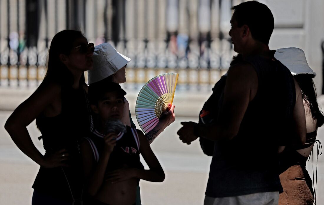 Turistas se protegem do sol enquanto visitam o Palácio Real no centro da cidade de Madri sob temperaturas muito altas, em 26 de junho de 2023, quando a Espanha enfrenta sua primeira onda de calor do verão, com temperaturas esperadas acima de 44 graus loca