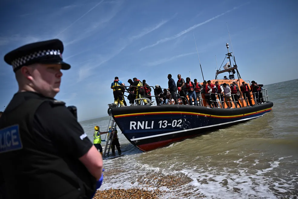 Policial observa chegada de embarcação no sul da Inglaterra com migrantes resgatados que tentavam cruzar o Canal da Mancha.