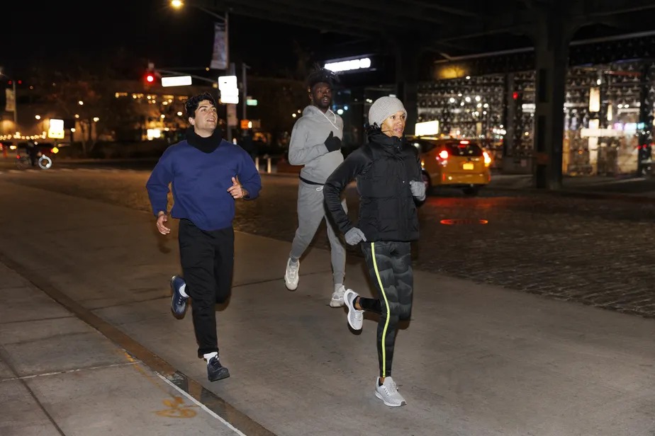 Amigos correm na rua à noite durante o inverno 