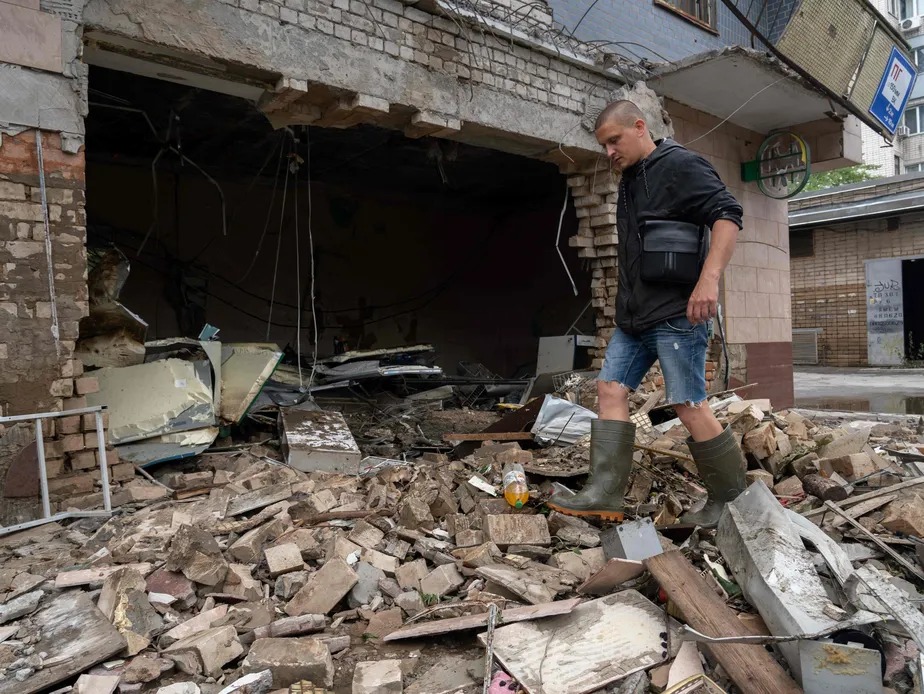 Um morador vasculha os escombros de uma loja destruída após bombardeio russo em Kherson 