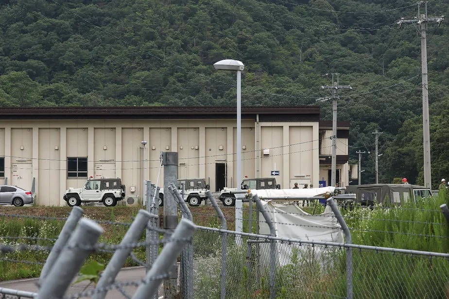 Veículos militares cercam prédio onde ocorreu um tiroteio no campo de treinamento militar de Hino, no Japão 