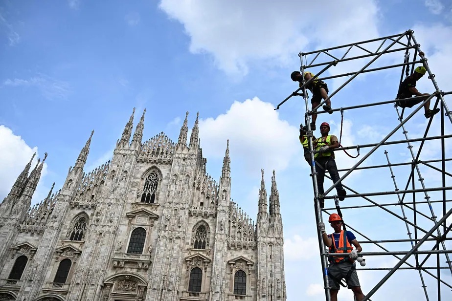 Trabalhadores instalam andaimes para tela gigante em frente à Catedral de Milão na véspera do funeral de Berlusconi 