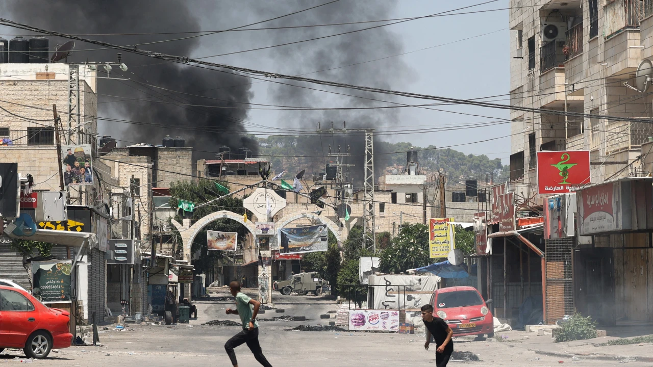 Palestinos correm para se proteger durante uma operação militar israelense na cidade de Jenin, na Cisjordânia ocupada.