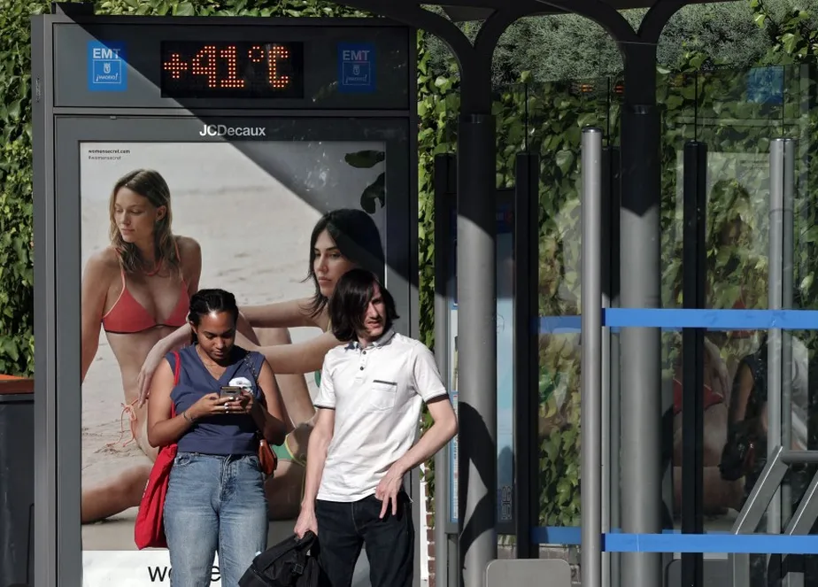 Pessoas aguardam em ponto de ônibus em Madri, onde termômetros marcam 41°C