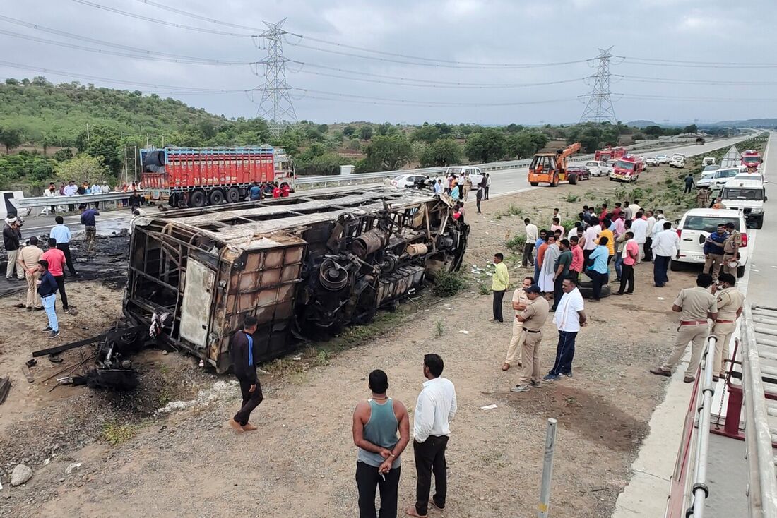 Pessoas se reúnem em torno dos destroços de um ônibus que pegou fogo