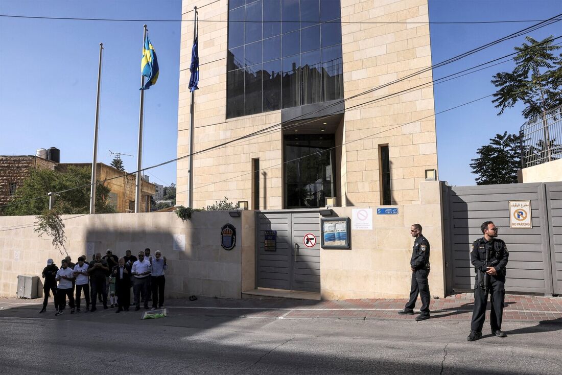 A polícia israelense de guarda enquanto manifestantes muçulmanos palestinos rezam durante uma manifestação do lado de fora da sede do consulado sueco