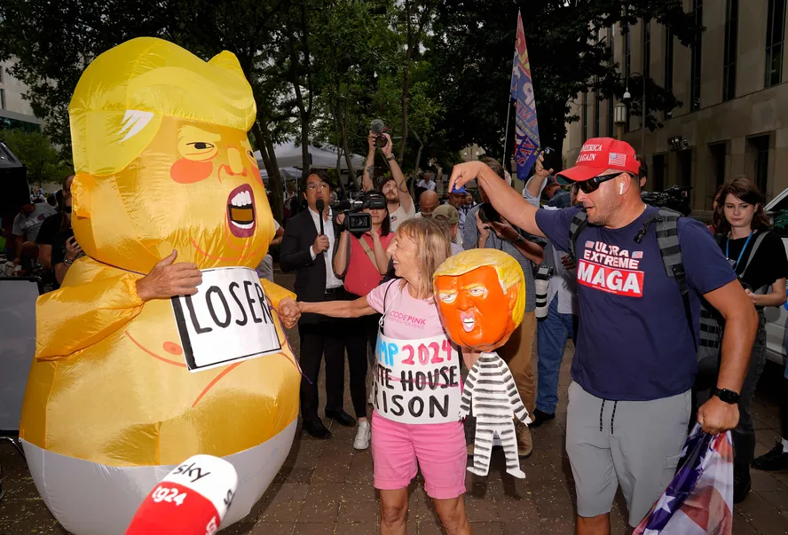 Uma pessoa com uma fantasia de Donald Trump vestido de bebê caminha em frente ao Tribunal E. Barrett Prettyman, em Washington, onde o ex-presidente ouvirá acusações criminais nesta quinta-feira.