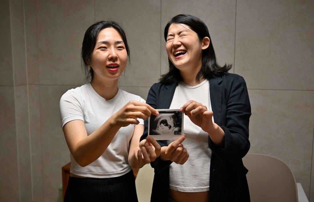 Casal de lésbicas sul-coreano posando com uma imagem de ultrassom fetal