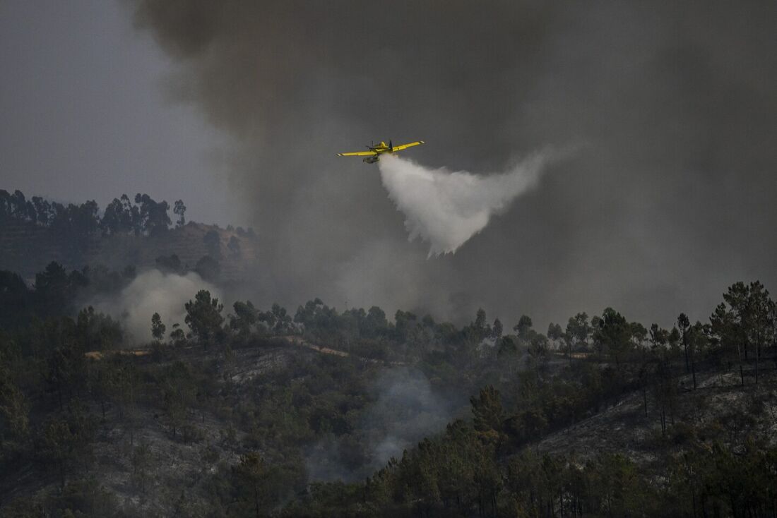 Avião de bombeiros joga água sobre um incêndio florestal em Odeceixe, sul de Portugal