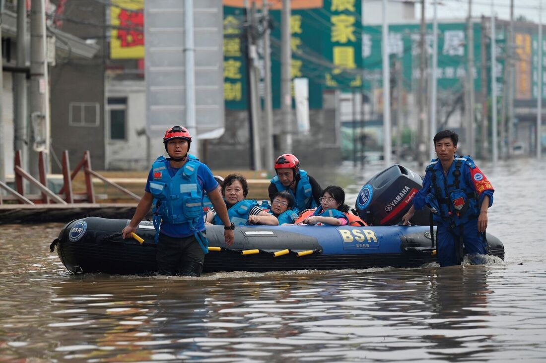 Equipes de resgate caminham em uma estrada inundada enquanto evacuam moradores