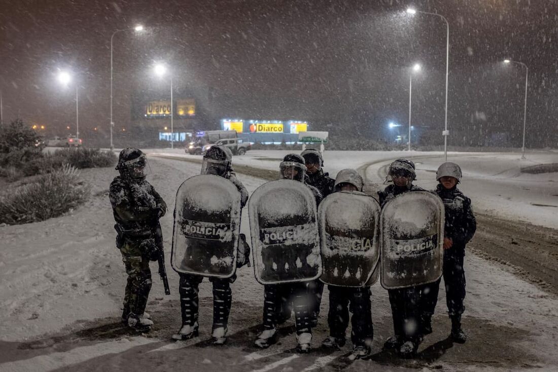 Policiais protegem um supermercado, sob neve após uma tentativa de saque, em Bariloche, Argentina