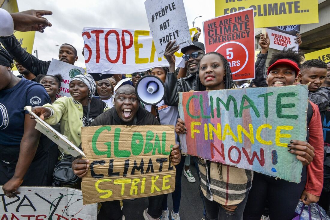 Ativistas climáticos seguram cartazes e entoam slogans enquanto participam numa marcha em Nairobi 