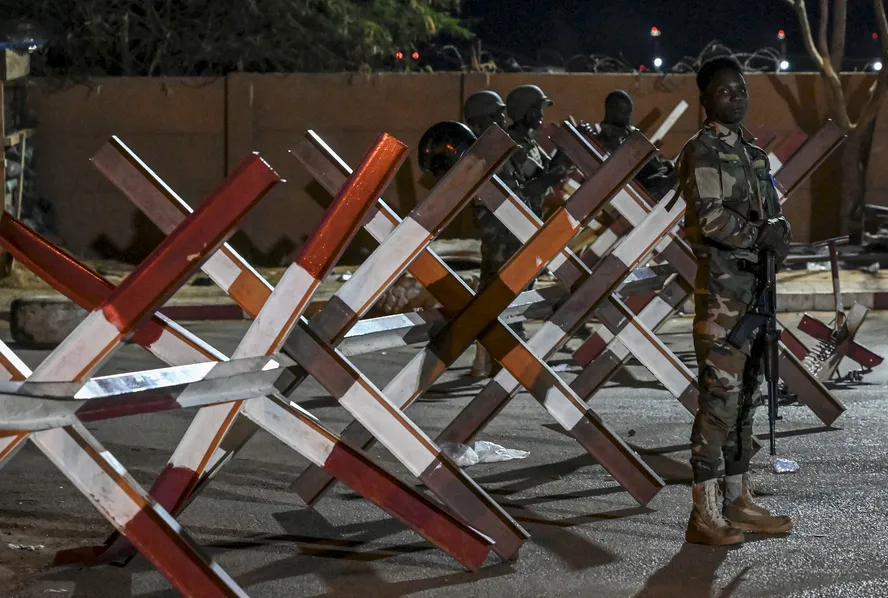 Um militar monta guarda enquanto apoiadores do Conselho Nacional para a Salvaguarda da Pátria do Níger protestam do lado de fora da base aérea francesa